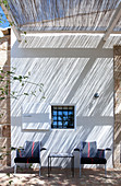 Shady seating area on roofed terrace outside Mediterranean country house