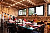 Festively set table and black, upholstered chairs in dining area of chalet