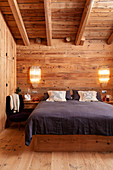 Double bed and elegant sconce lamps in bedroom in chalet
