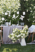 Gedeckter Tisch in Weiß und Beige im Garten vorm Schneeball-Strauch