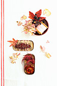 Blech- und Bakelitdose dekoriert mit Blüten, Blättern, Brosche und Garnrolle