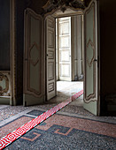 Strip of modern, red-and-white tiles on antique mosaic floor