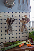 Kitchen utensils stored in swing-top jars hung on wall