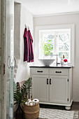 Old, restored cabinet used as washstand below window