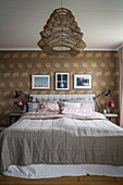 Bed in bedroom with floral art nouveau wallpaper