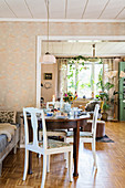 Runder, antiker Tisch mit Landhaus-Stühlen in hellem Esszimmer