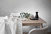 White tablecloth, cutlery, carafe and eucalyptus branch on table