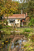 Yellow summerhouse and pond in late summer garden