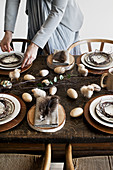 Woman setting old wooden table with rustic natural decorations