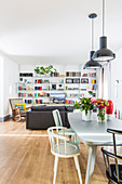 Dining area and seating area with sofa and bookcase in open-plan interior