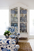 Blue-and-white armchair in front of white, antique cupboard