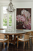 Table with marble top and chairs in front of floral artwork in dining area