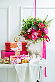 Wandkranz mit Rosenblüten davor verpackte Weihnachtsgeschenke