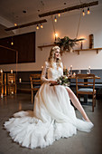 Braut in weißem Brautkleid mit Schleppe im Restaurant mit Vintage-Flair