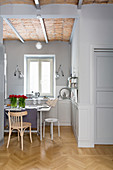 Dining table in open-plan kitchen with grey walls and parquet floor