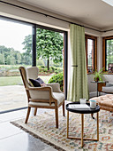 Sessel und runder Beistelltisch vor Terrassentür im Wohnzimmer