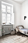 Holzbett und Buchstabe 'P' an weißer Wand im Kinderzimmer