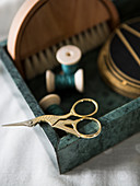 Golden scissors on green stone tray of sewing utensils