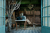 View through open double doors into summerhouse with antique gardening equipment