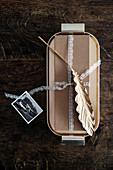 Wrapped gift decorated with golden leaf and lace ribbon on tray
