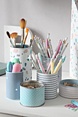 Tin cans covered with pastel paper on desk