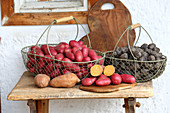 Colourful potatoes in wire baskets on rustic wooden bench