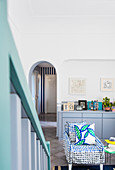 View past staircase to blue-and-white, polka-dot, loose-covered armchair and pale grey sideboard