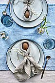 Easter bunnies made from eggs wrapped in napkins on table set in blue