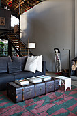 Vintage trunk used as coffee table, sofa and skeleton figurine in front of staircase