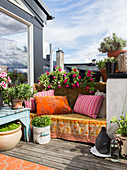 Colourful blanket and cushions on bench on roof terrace