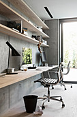 Fitted desk and shelves made from wooden boards on concrete wall