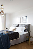 Bed with grey valance and chandelier in elegant, hotel-style bedroom