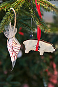 Sweets in organza sachet and decoration in shape of pig hung on Christmas tree