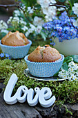Lettering spelling 'Love' next to muffins on moss