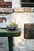 Bowl of grapes on battered green stool in front of old wall