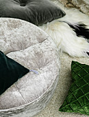 Velvet cushions in grey and green on fur blanket on rug