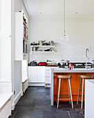 Island counter and orange accents in large, open-plan kitchen