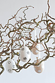 Ausgeblasene Eier mit Stempelmotiv an Zweigen hängend