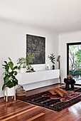 White floating sideboard, modern artwork and houseplants in living room
