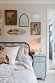 Vintage-style mirrors and pictures above metal bed in bedroom