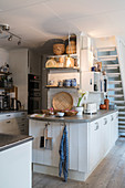 Island counter used as partition in white, open-plan, country-house kitchen
