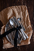 Silver cutlery tied with bow on tray on brown cloth