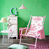 Deck chair with toile-de-jouy fabric seat in front of green wall