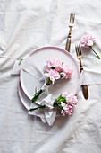 Posies of pink carnations tied with ribbons on plates