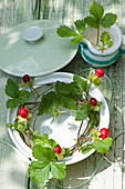 Tendrils of mock strawberries in soup tureen and wild strawberry flowers in milk jug decorating table