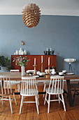 White spoke-back chairs around wooden table in front of blue wall in dining room