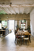 Vintage wooden table and chairs in restaurant with rustic ceiling and potted houseplants on shelves in window