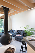 Moderne Wohnzimmereinrichtung mit hängendem Kamin und dunklem Sofa