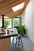 Modern kitchen with wooden ceiling, bar stools and view of the yard