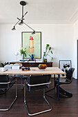 Dining area with wooden table, black chairs and modern lamp